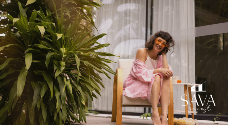 Mulher jovem sorrindo em varanda com plantas, transmitindo bem-estar e estilo de vida saudável em ambiente residencial