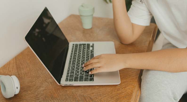 Pessoa usando notebook em casa para acessar o site da Sava Invest e acompanhar o anúncio do imóvel.